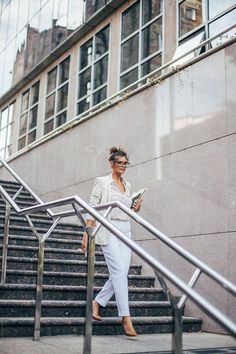 a woman is walking down the stairs while looking at her cell phone and reading something