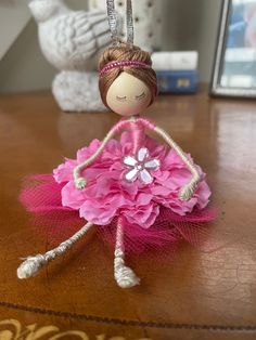 a doll is sitting on top of a table with pink flowers in her hair and wearing a tiara