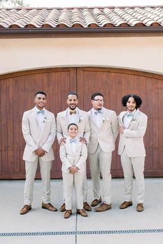 a group of men standing next to each other in front of a wooden garage door