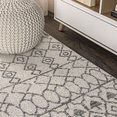 a white and gray rug on the floor next to a dresser