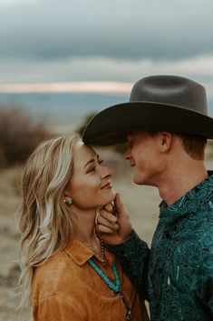 a man in a cowboy hat standing next to a woman wearing a brown shirt and turquoise necklace