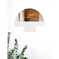 a plant in front of a mirror with a brick wall behind it and an arch over the mirror