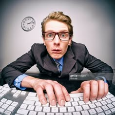 a man wearing glasses is sitting at a computer keyboard with his hands on the keyboard