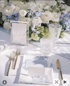 the table is set with white and blue flowers