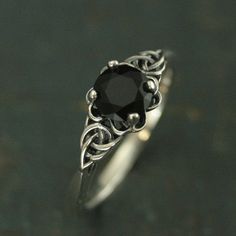 a black diamond sits on top of a silver ring with filigrees around it