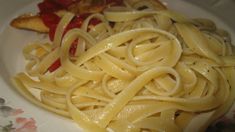 a plate with some pasta on it and sauce in the middle, next to bread