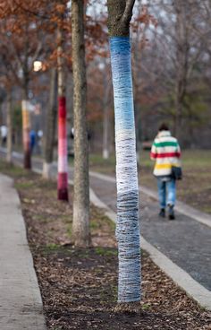 someone is walking down the street with their cell phone in hand and an image of a tree on the sidewalk