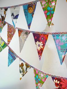 colorful buntings hanging from the ceiling in front of a white wall with flowers on them