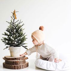 a baby is playing with a small christmas tree