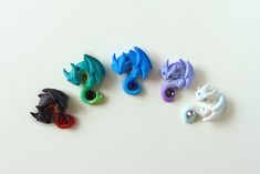 five different colored dragon magnets sitting on top of a white surface with one facing the camera