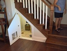 a woman standing next to a stair case in a room with wooden floors and white railings