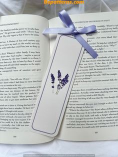 an open book with blue flowers on it and a ribbon tied around the bookmark