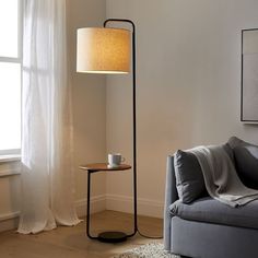 a living room with a couch, table and lamp next to a window in the corner