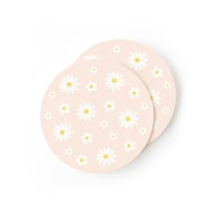 two pink coasters with white and yellow flowers on the front, one is round