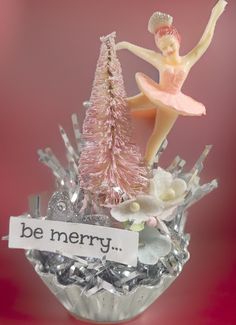 a christmas ornament with a ballerina figure on top of it and a sign that says be merry