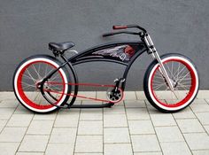 a black and red bike sitting on top of a brick floor next to a wall