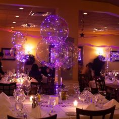 a dining room filled with lots of tables covered in white tablecloths and balloons