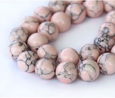 a strand of pink and black marble beads on a white surface with one bead in the middle