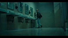 a man standing in a bathroom next to urinals with sinks on either side