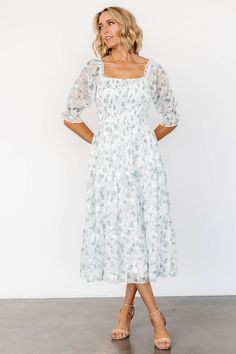 Baltic Born exclusive style Classic Off-White background with Sage Green florals Square neckline with ruffled elastic Smocked bodice, great for any bust size Semi-sheer smocked poet sleeves Sleeves can be worn on or off the shoulder Tiered midi length skirt Midi length lining with unlined sleeves Please note that light colored dresses may appear semi-transparent in certain lightings. We recommend wearing nude undergarments and/or a slip underneath. 100% Polyester Trina is 5'6, cup size 32D, size 2 and is wearing size S Fitted White Dress With Elastic Neckline, Fitted Square Neck Dress With Elastic Neckline, Fitted Dress With Elastic Neckline For Garden Party, Fitted Midi Dress With Elastic Neckline For Brunch, Light Colored Dresses, Baltic Born, Skirt Midi, White Backdrop, Midi Length Skirts