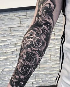 a man's arm with black and grey tattoos on it, which has roses in the middle