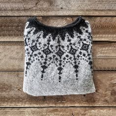 a white and black sweater hanging on a wooden wall