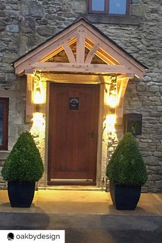 a house with two large planters in front of it and lights on the door