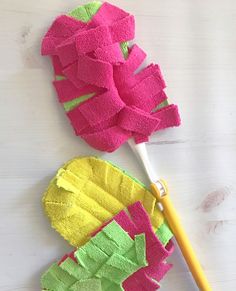 two pink and green flower shaped objects on a white wooden surface with a yellow handled toothbrush