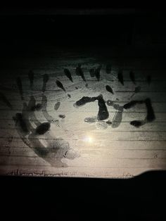 the shadow of a hand print is cast on a window sill in the dark