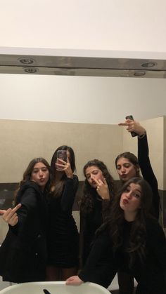 a group of young women standing in front of a bathroom mirror taking a selfie