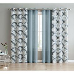 a blue and white curtain hanging in front of a window with a vase on the floor