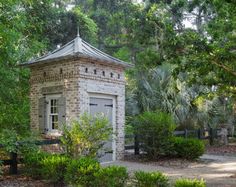 a small brick building surrounded by trees and bushes