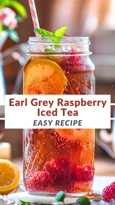 a jar filled with iced tea next to lemons and raspberries