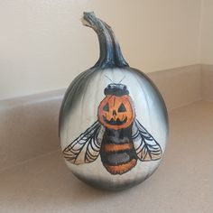 a painted pumpkin sitting on top of a counter next to a wall with a bee drawn on it