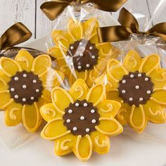 decorated cookies in the shape of sunflowers on a white plate with gold ribbon