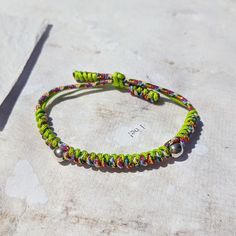 a green bracelet with multicolored beads and a silver bead hook on it