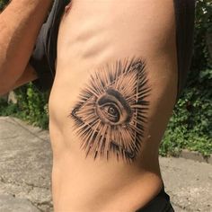 a man with an all seeing eye tattoo on his stomach and chest is standing in front of some bushes