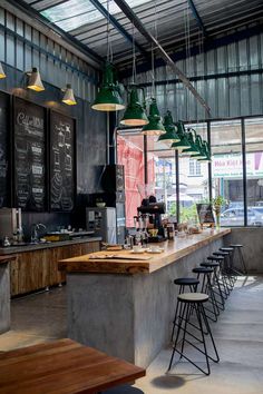 a restaurant with chalkboard menus hanging from the ceiling and bar stools at the counter