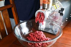 the ground beef is being processed in a bowl with a meat grinder behind it