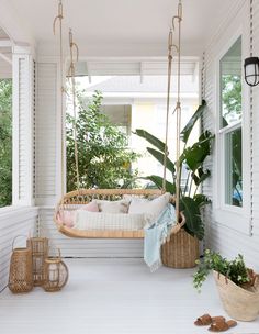 a white porch with a swing chair and potted plants