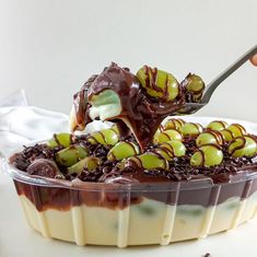 someone is scooping some kind of dessert with chocolate and green toppings on top