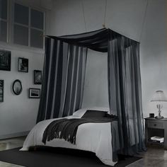 a black and white bedroom with four poster bed