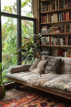 a couch sitting in front of a book shelf filled with lots of books next to a window