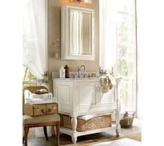 a bathroom with a sink, mirror and two suitcases in front of the window