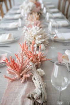 the table is set with corals and place settings for two people to sit at