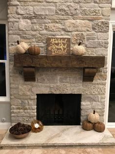 a stone fireplace with pumpkins and other decorations on the mantel above it in a living room