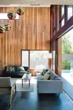 a living room filled with furniture next to a wooden wall