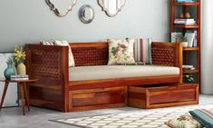 a wooden daybed with drawers underneath it in front of a white rug and bookcase