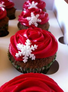 cupcakes with red frosting and white snowflakes on them are lined up