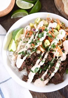 a white bowl filled with meat and rice covered in sauce, garnished with cilantro